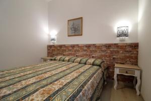 1 dormitorio con cama y pared de ladrillo en Premium Apartments Peschiera, en Peschiera del Garda