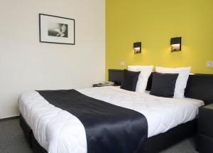 a hotel room with a large bed with black and white pillows at Hotel Adoma in Ghent