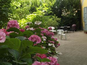 un jardín con flores rosas, mesas y sillas en Villa Ghia Appartamento en Parma
