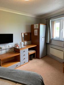 a bedroom with a desk and a refrigerator and a sink at Tafarn Y Rhos in Llangefni