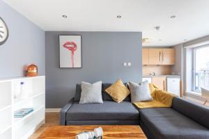 a living room with a gray couch and a kitchen at Merchant City Modern 1 Bed Executive Flat in Glasgow