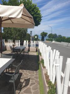 a row of tables and chairs with an umbrella at Hotel La Favorita in Peschiera del Garda
