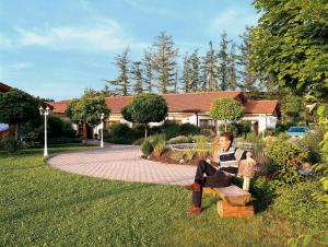 a woman sitting on a bench in a yard at Hotel Christl in Rohrdorf