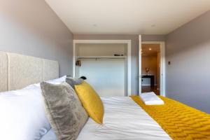格拉斯哥的住宿－Stunning 1 Bed Merchant City Apartment with Parking，卧室配有白色床和黄色毯子
