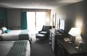 a hotel room with two beds and a chair and a television at Ramada by Wyndham in Quesnel