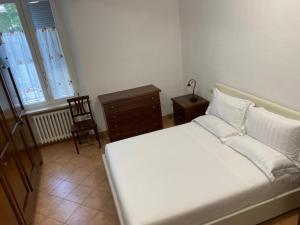 una camera con un letto bianco e una sedia di B&B Giulia a Parma