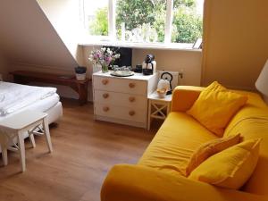 a yellow couch in a bedroom with a bed and a window at Bed & Breakfast de Echo in Muiderberg