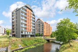 een appartementengebouw met een brug over een rivier bij Aura III Apartments & Free Parking by Downtown Apartments in Gdańsk +28 foto's