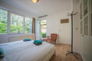 een slaapkamer met een bed, een stoel en ramen bij Amsterdam Beach in Zandvoort