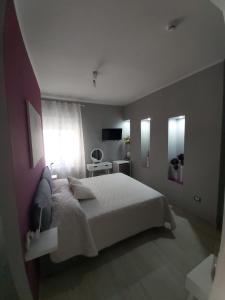a bedroom with a large white bed and a table at Le stanze di Dalia in Crotone