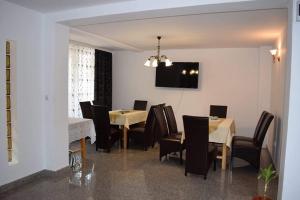 a dining room with tables and chairs and a television at Casa Visescu in Băile Herculane