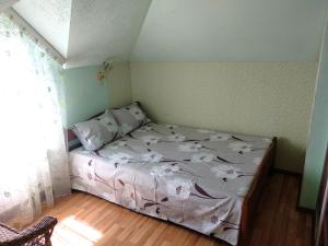 Un pequeño dormitorio con una cama con flores. en Садиба у затишку en Svityazʼ