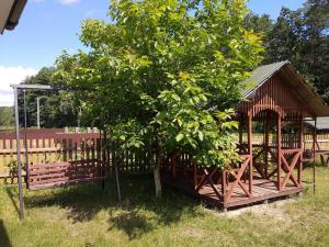 einen hölzernen Pavillon neben einem Baum in der Unterkunft Садиба у затишку in Switjas