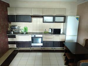 cocina con electrodomésticos blancos y mesa negra en Садиба у затишку, en Svityazʼ
