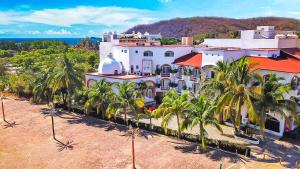 un grand bâtiment blanc avec des palmiers devant lui dans l'établissement Hotel Bahia Huatulco, à Santa Cruz Huatulco