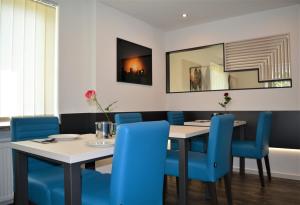 a dining room with a table and blue chairs at Hotel BaWü in Stuttgart