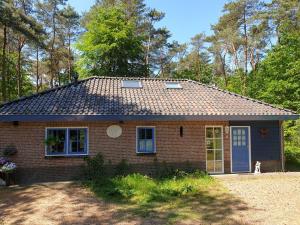 a small red brick house with blue doors and windows at Holiday home bos en heide in Otterlo