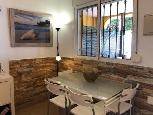 a dining room with a glass table and white chairs at Apartamentos casa Tia Antonia in Málaga
