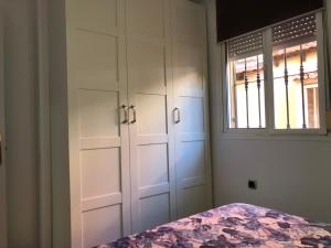 a bedroom with white cabinets and a window at Apartamentos casa Tia Antonia in Málaga