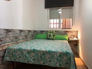 a bedroom with a bed with green sheets and a window at Apartamentos casa Tia Antonia in Málaga