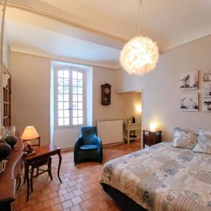 een slaapkamer met een bed, een stoel en een kroonluchter bij Maison de Maître Des-Sens in Nyons