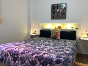 a bedroom with a bed with a purple comforter at Apartamentos casa Tia Antonia in Málaga