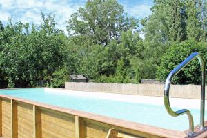 una piscina con una valla de madera y árboles en Angele & Auguste, en Nervezain