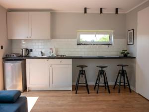 a kitchen with white cabinets and bar stools at Różany Domek in Grudziądz