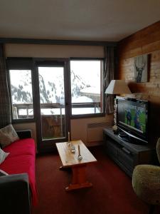 a living room with a red couch and a tv at Coquet studio Quartier Falaise superbe vue in Avoriaz