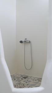 a shower in a white bathroom with a tile floor at Pepi's Rooms in Triovasálos