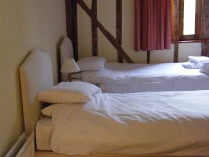 a room with three beds with white sheets and a lamp at Warmans Barn in Stansted Mountfitchet