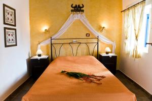 a bedroom with a bed with an orange blanket and flowers on it at Pepi's Rooms in Triovasálos