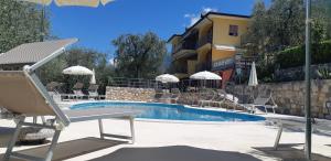 a swimming pool with chairs and a hotel at Villa Due Leoni - Residence in Brenzone sul Garda
