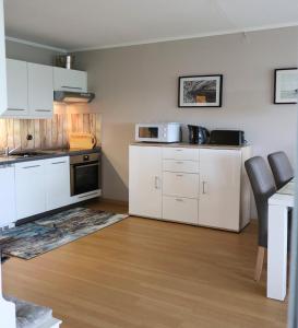 una cocina con armarios blancos y electrodomésticos negros en Schicke FeWo 150m vom Strand kostenlos WLAN großes Schwimmbad Sauna en Cuxhaven