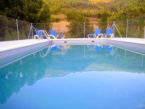 a swimming pool with blue chairs in the water at Casa Rural el Rincón in Perarrua