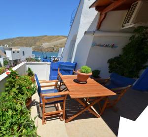 a wooden table and chairs on a balcony with a plant at Aegeon Pension in Aegiali