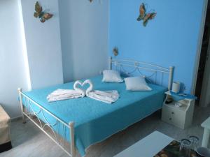 a blue bedroom with a bed with towels and butterflies at Aegeon Pension in Aegiali