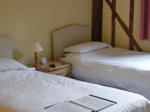 a room with two beds and a table with a lamp at Warmans Barn in Stansted Mountfitchet