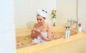 a woman sitting in a bath tub looking at her cell phone at Saravoan Royal Palace in Phnom Penh