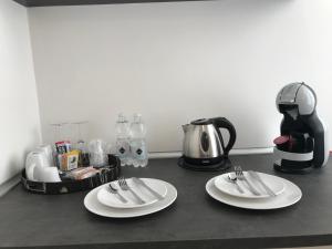 um balcão com dois pratos brancos e uma cafeteira em Alba rooms em La Spezia
