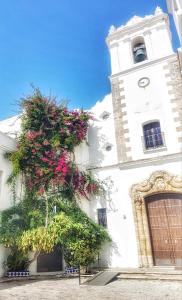 Un edificio con una torre dell'orologio con dei fiori sopra di El Beaterio a Tarifa