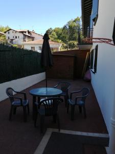 een patio met een tafel en stoelen en een parasol bij Arrantzaleak in Hendaye