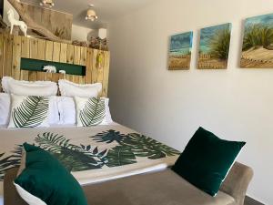 een slaapkamer met een bed met groene en witte kussens bij B&B La Terre Brûlée in Aigues-Mortes