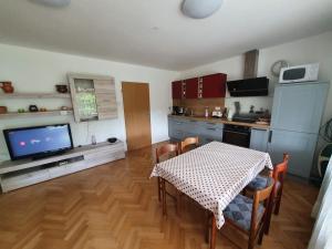 a living room with a table and a kitchen with a television at Apartma Meta in Radovljica