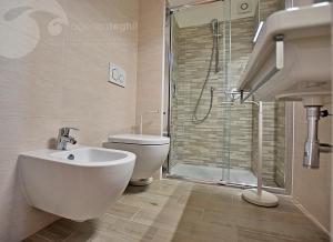 y baño con aseo, lavabo y ducha. en Condominio Lory, en Lignano Sabbiadoro