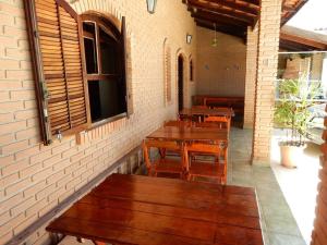 a patio with wooden tables and benches in a building at Casa do Sergio in Caraguatatuba