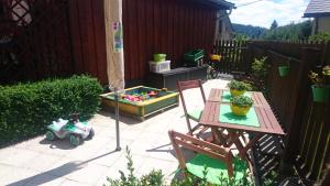 een patio met een tafel en stoelen en een speelgoedauto bij Ferienwohnung mit Garten und Spielplatz in Klingenthal