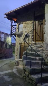 un edificio de piedra con una escalera que conduce a una puerta en A Paragűeria, en Sas de Penelas