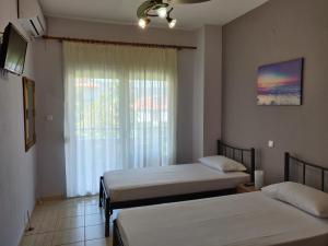 two beds in a room with a window at Methexis Apartment in Skala Potamias