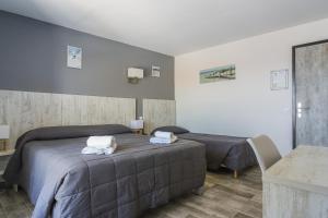 a bedroom with two beds with towels on them at Hotel Les Palmiers En Camargue in Saintes-Maries-de-la-Mer